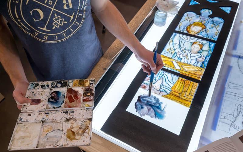 A students paints a luminaire — a mockup of the window painted onto clear acetate and framed, 这样光线就能穿透它 